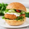 Delicious grilled chicken sandwich with fresh cucumbers, lettuce, and tomato on a sesame bun.